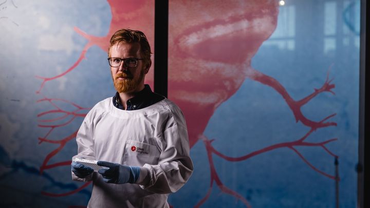 A scientist stares into the camera