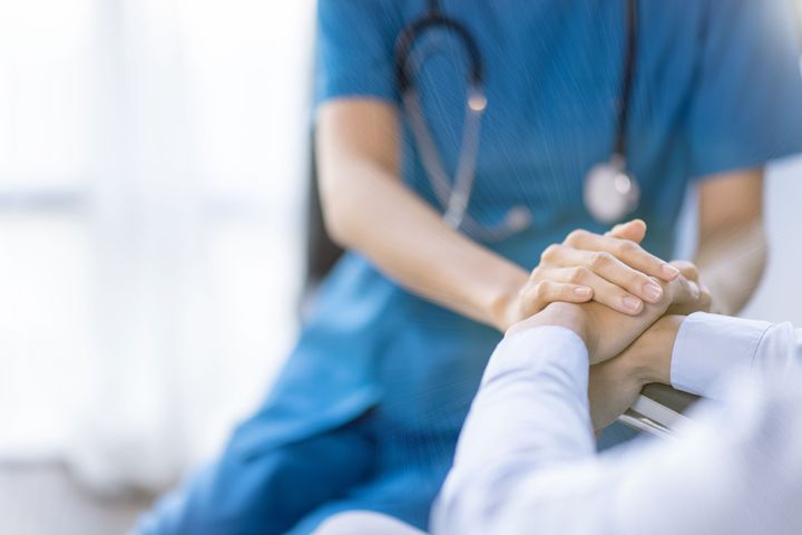 A doctor holds a patient's hands